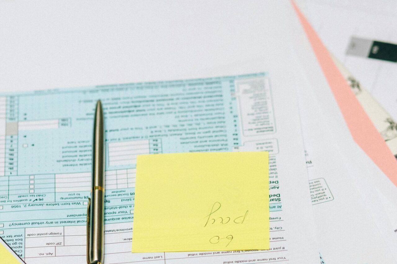 Close-up of tax documents with a calculator, pen, and notes, ideal for financial content.